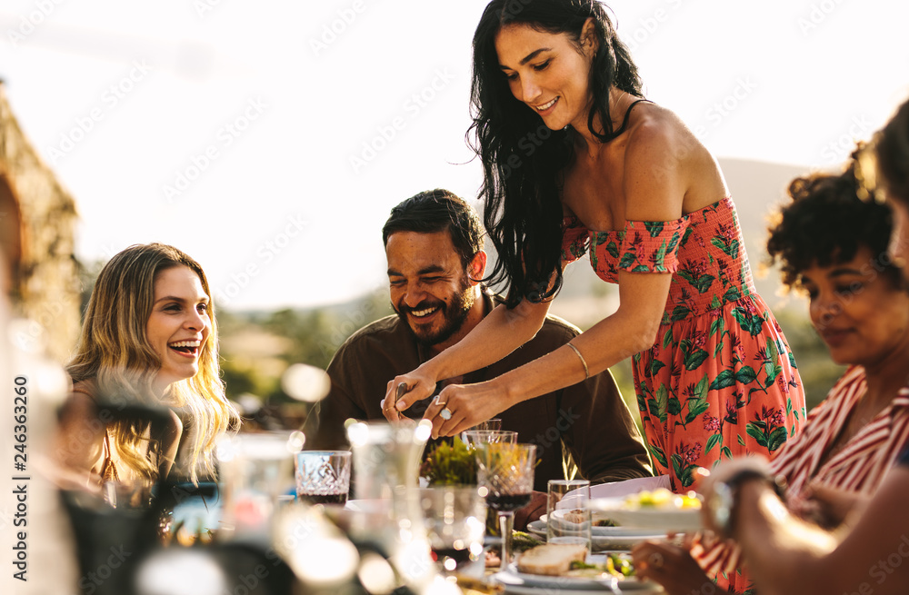 Fototapeta premium Beautiful woman serving food to friends