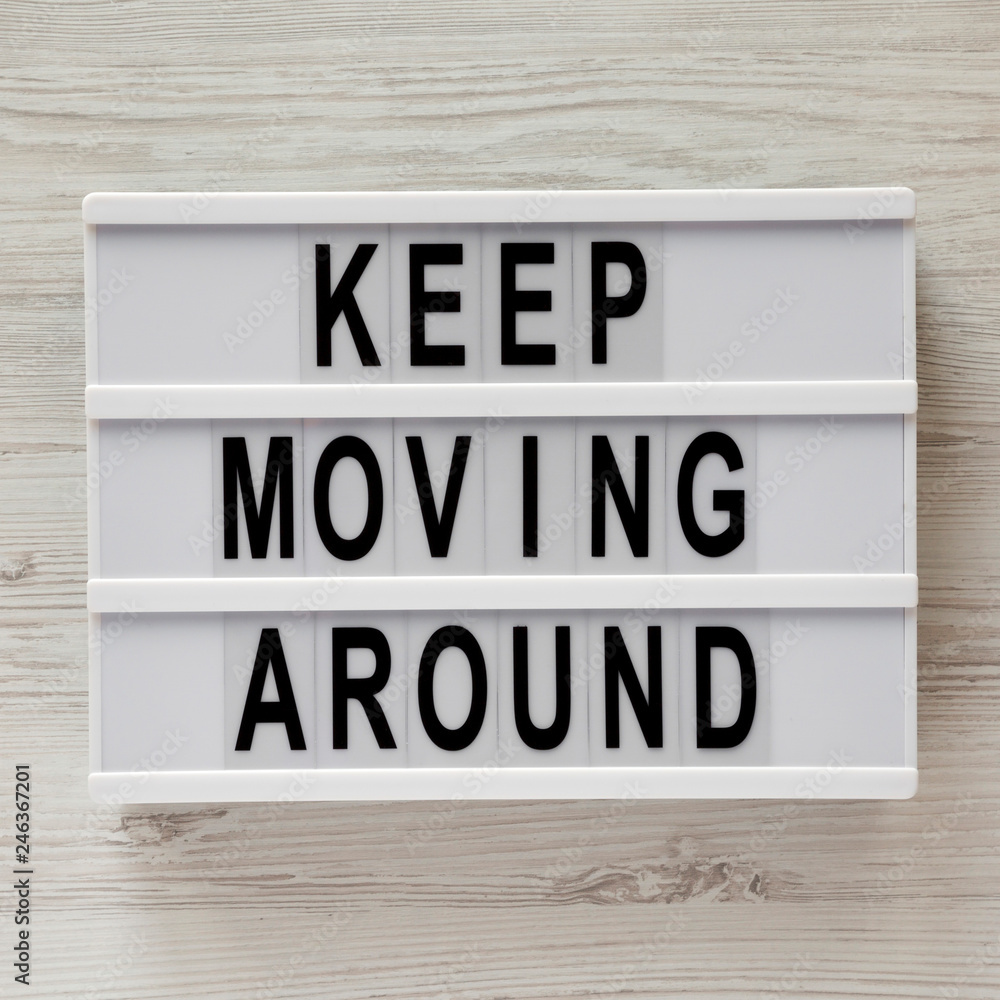 Lightbox with text 'Keep moving around' over white wooden background, overhead view. From above, flat lay, top view. Lightbox with text 'Keep moving around' over white wooden background, overhead view. From above, flat lay, top view.