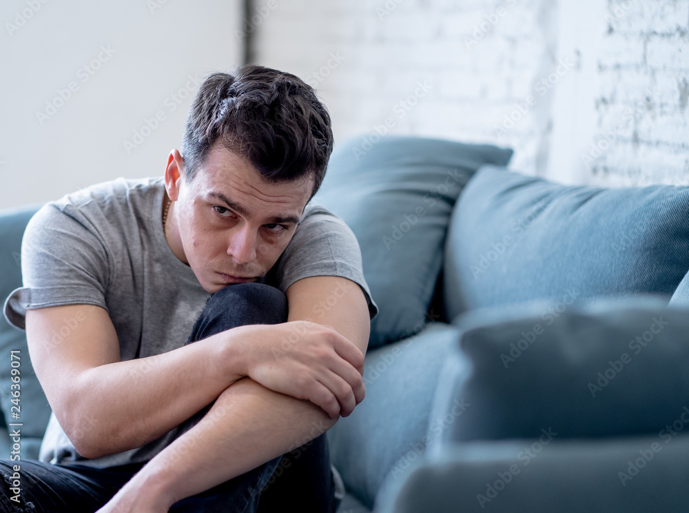 Young man suffering from depression lying on sofa alone at home feeling frustrated and hopeless Young man suffering from depression lying on sofa alone at home feeling frustrated and hopeless