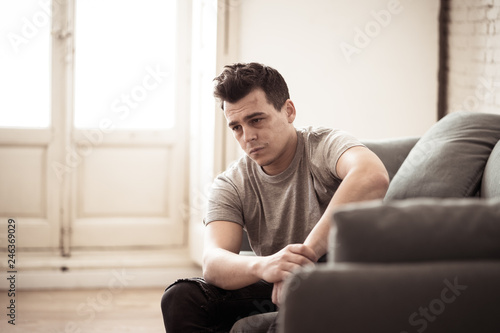Young attractive man suffering from depression in emotional pain lying on couch at home