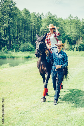 Couple riding a horse in the farm in cowboy style. Sport, happiness, hobby concept © Andreshkova Nastya