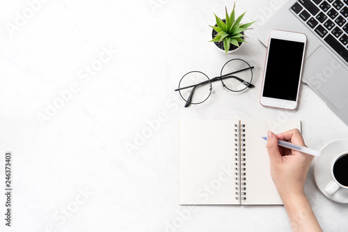 Obraz na plátne A woman is writing notes isolated on stylized marble office working desk with sm