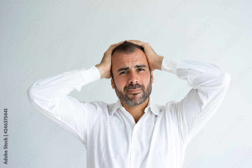 Tensed handsome man looking at camera and clutching head. Worried middle-aged guy. Problem concept. Isolated front view on white background. Tensed handsome man looking at camera and clutching head. Worried middle-aged guy. Problem concept. Isolated front view on white background.