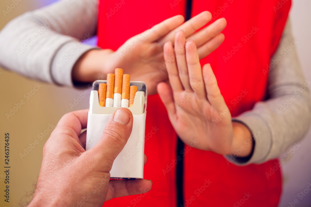 Fototapeta premium Quitting smoking concept. Hand is refusing cigarette offer. People, stop smoking and healtcare concept