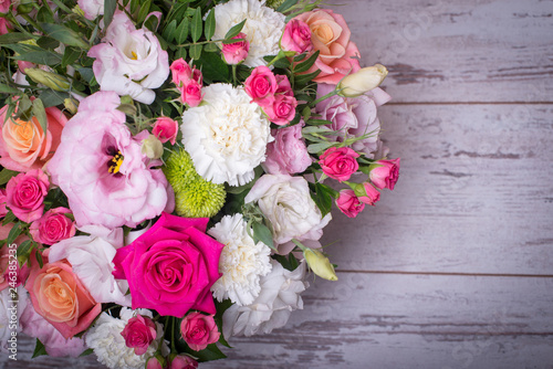 beautiful floral arrangement in the box, pink and yellow rose, pink eustoma, green and pink chrysanthemum, white carnation, dahlia on wooden background, top view, with space for text © Alex