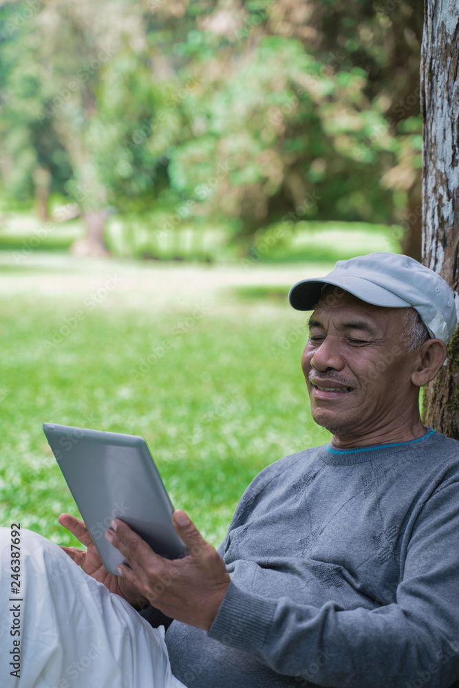 senior old man using tablet pc in the park senior old man using tablet pc in the park