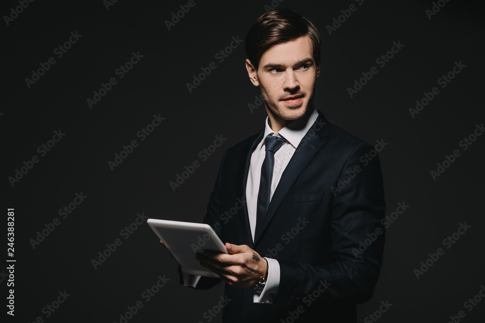 handsome businessman holding digital tablet in hands isolated on black handsome businessman holding digital tablet in hands isolated on black