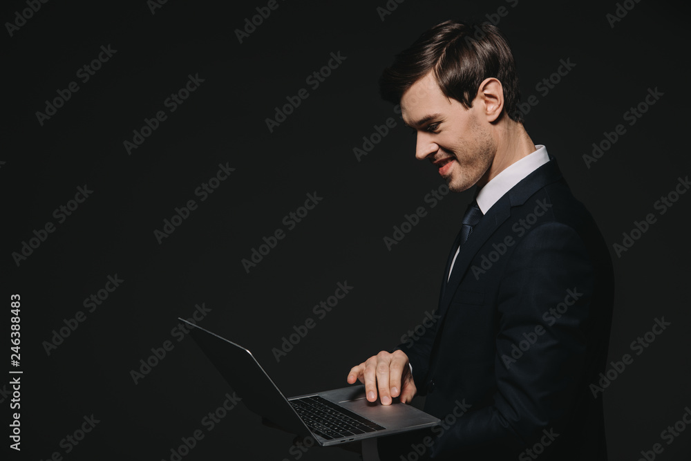 handsome businessman using laptop isolated on black handsome businessman using laptop isolated on black
