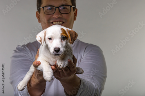 Horizontal portrait of handsome cheerful man holds jack russell terrirer, has glad expression photo