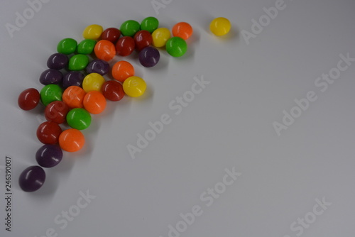 Bright sweet and tasty candy, yellow, cherry, orange, green and purple dragee on a white background