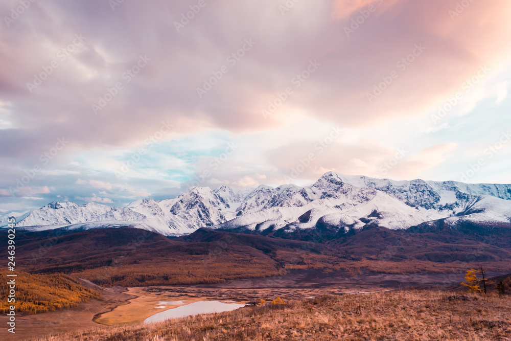 Pink and purple clouds over mountain range. Sunset or dawn in mountains in autumn. Hiking trip to valley of mountains. Pink and purple clouds over mountain range. Sunset or dawn in mountains in autumn. Hiking trip to valley of mountains.