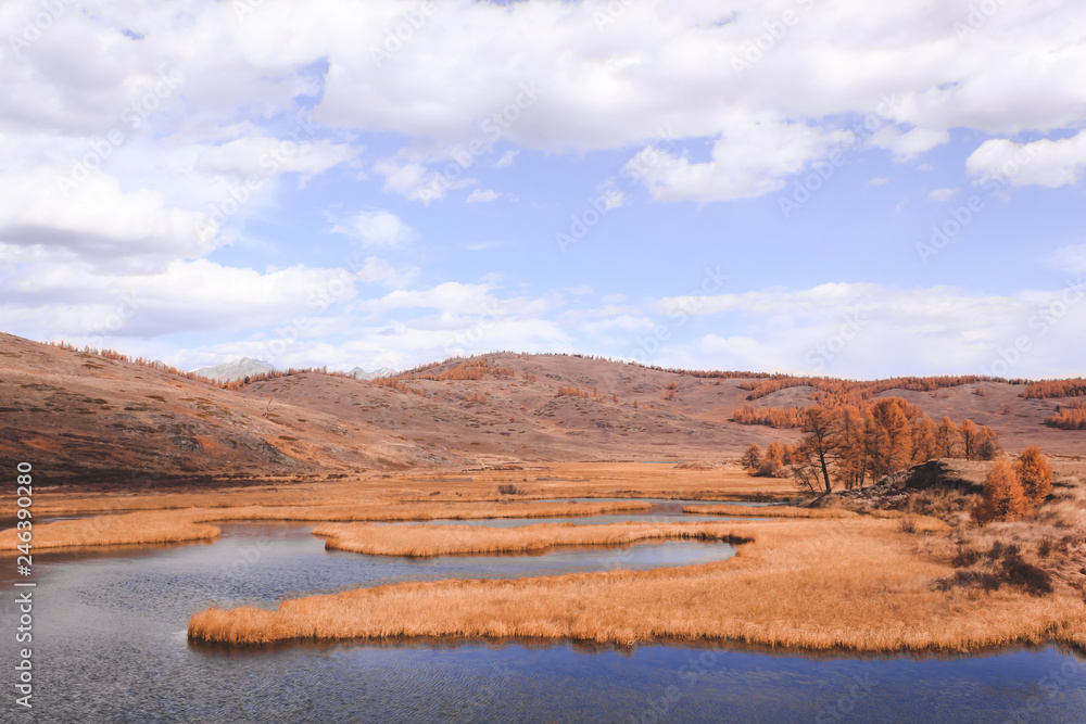 Autumn panorama. View of mountains and lake. Mountain range on horizon. Travel to mountain valley with rivers.