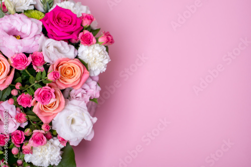 beautiful floral arrangement in the box  pink and yellow rose  pink eustoma  green and pink chrysanthemum  white carnation  pink dahlia on pink background with space for text.