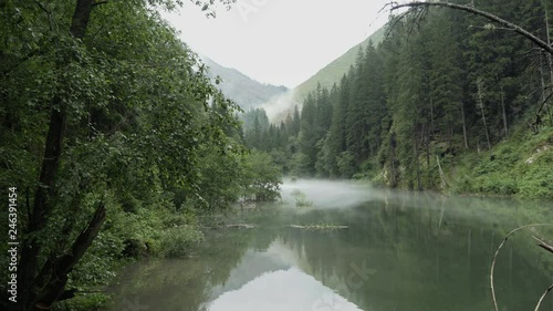 Mountain lake, foggy peaceful atmosphere. Place for alpine hiking, walking, swimming, sports and leisure activities. Wading water level. Day stabilized v-log shot