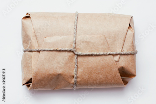 Box parcel wrapped in brown craft paper   tied hemp cord on white background. 