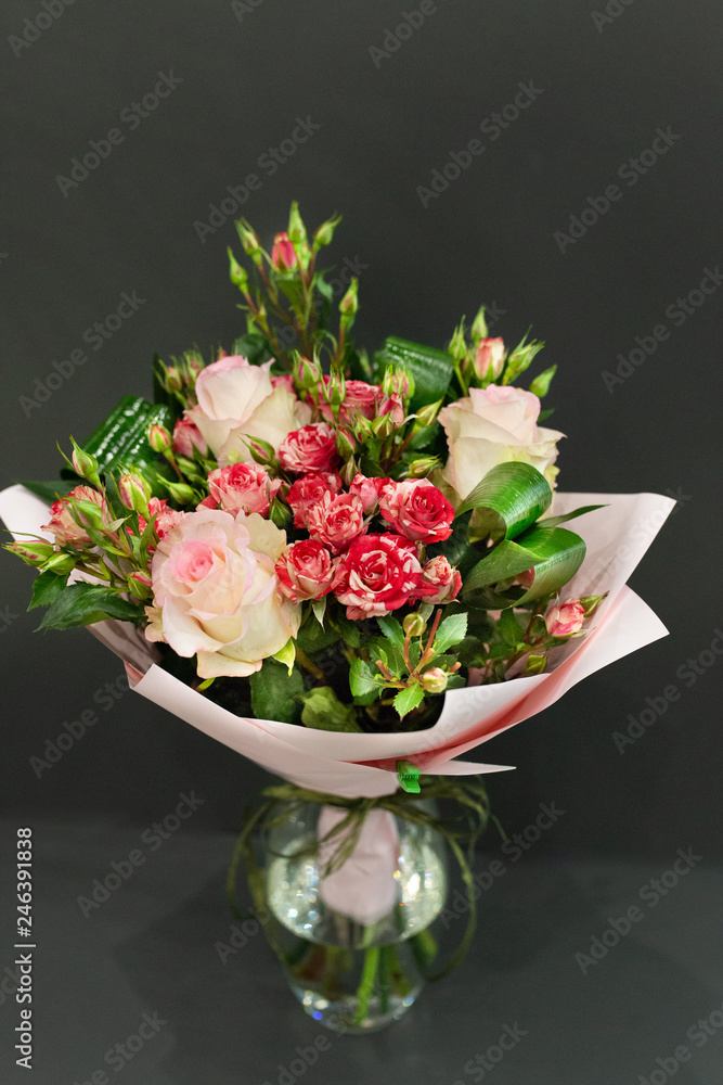 Bright bouquet of bright colors in paper packaging against a gray background. Bright bouquet of bright colors in paper packaging against a gray background.