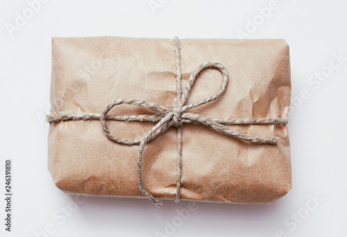 Box parcel wrapped in brown craft paper   tied hemp cord on white background. 
