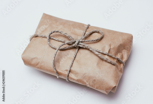 Box parcel wrapped in brown craft paper tied hemp cord on white background. 