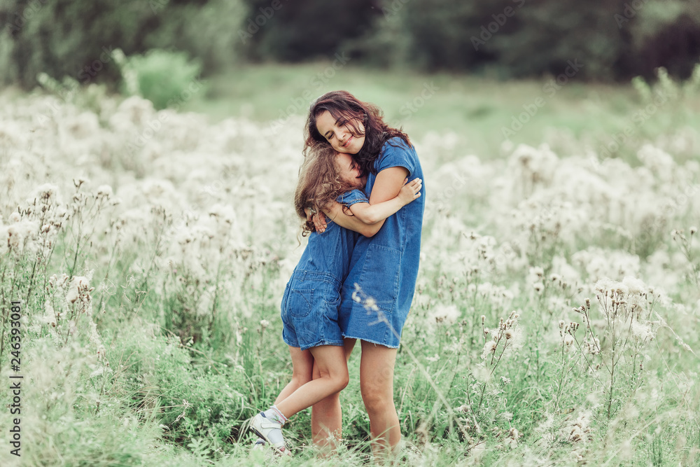 Happy mother and daughter outdoors in the summer having fun together. Motherhood, love, family, happiness concept