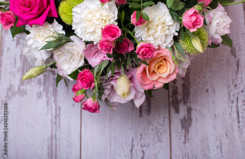 beautiful floral arrangement in the box  pink and yellow rose  pink eustoma  green and pink chrysanthemum  white carnation  dahlia on wooden background  top view  with space for text