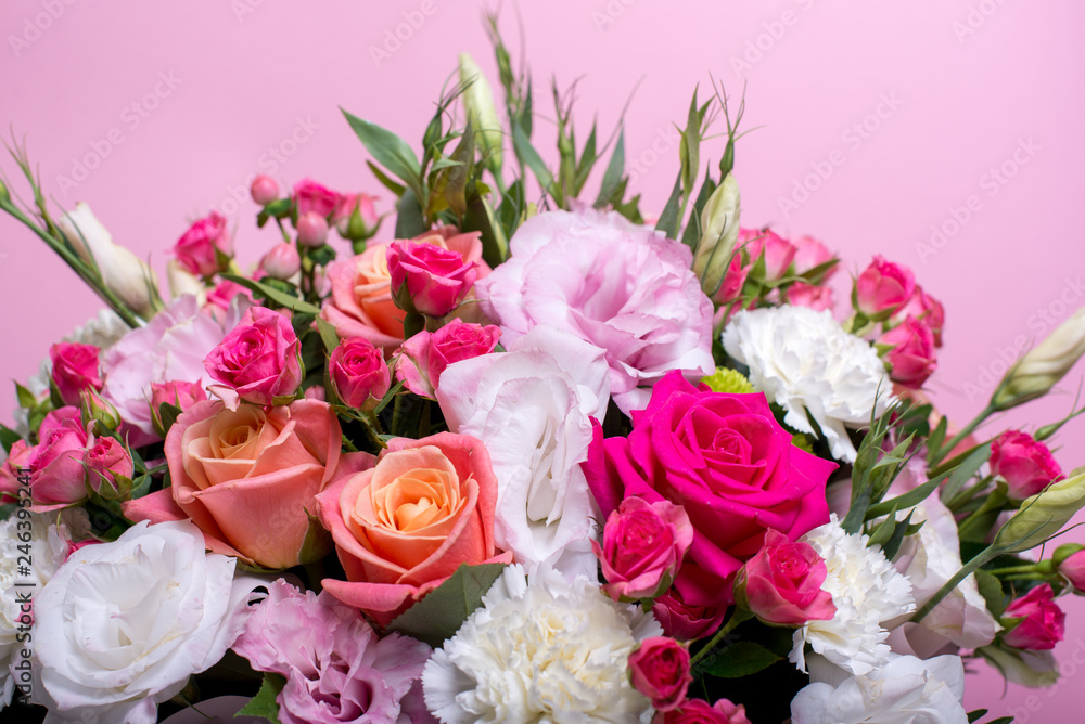 beautiful floral arrangement in the box, pink and yellow rose, pink eustoma, green and pink chrysanthemum, white carnation, pink dahlia on pink background with space for text.