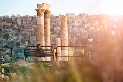 Cuadro en lienzo A girl is seated on a bench admiring the magnificent landscape from the Citadel of Amman in Jordan