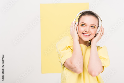 smiling stylish girl in headphones listening music with copy space and limelight on background photo