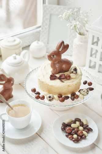 Rustic Easter Cake with Chocolate bunnies and Eggs. Easter greeting card background  closeup with copy space. Easter sweets for children. Chocolate bunny on decorated cake stand for Easter brunch.