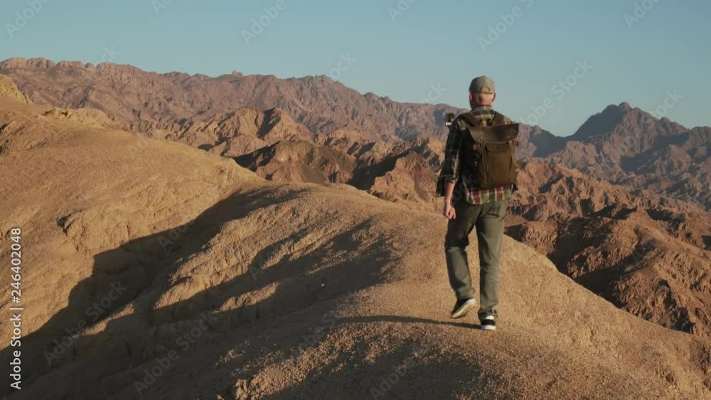 Senior male traveler walking on a desert rock with selfie stick handheld shot Senior male traveler walking on a desert rock with selfie stick handheld shot