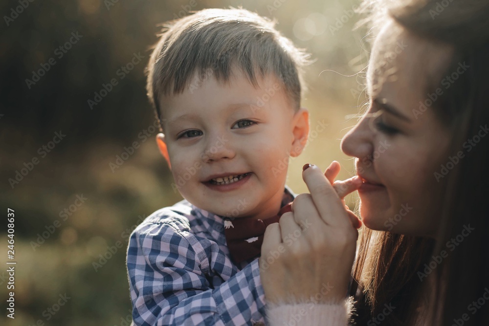 Portrait of handsom happy young boy with his mom. Mom is kissing his hands. Son is looking at the camera and smiling. Portrait of handsom happy young boy with his mom. Mom is kissing his hands. Son is looking at the camera and smiling.