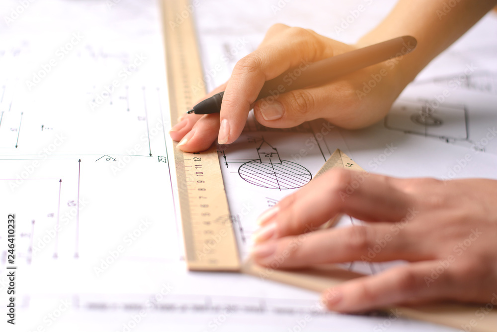 Girl architect draws a plan, graph, design, geometric shapes by pencil on large sheet of paper at office desk. Soft focus Girl architect draws a plan, graph, design, geometric shapes by pencil on large sheet of paper at office desk. Soft focus