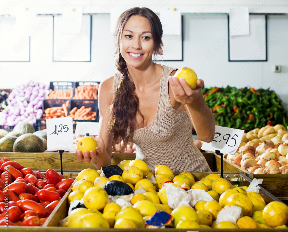 Obraz premium Female customer buying lemons on fruit market