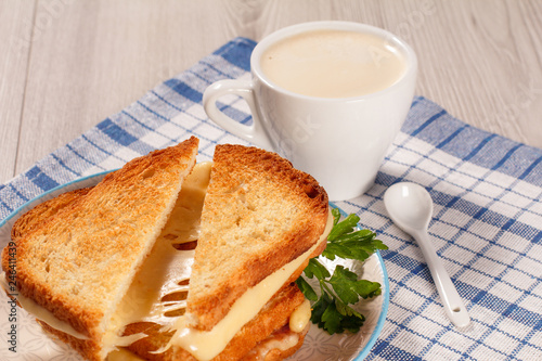 Toasted slices of bread with cheese and green parsley on white plate  cup of coffee and spoon on napkin.