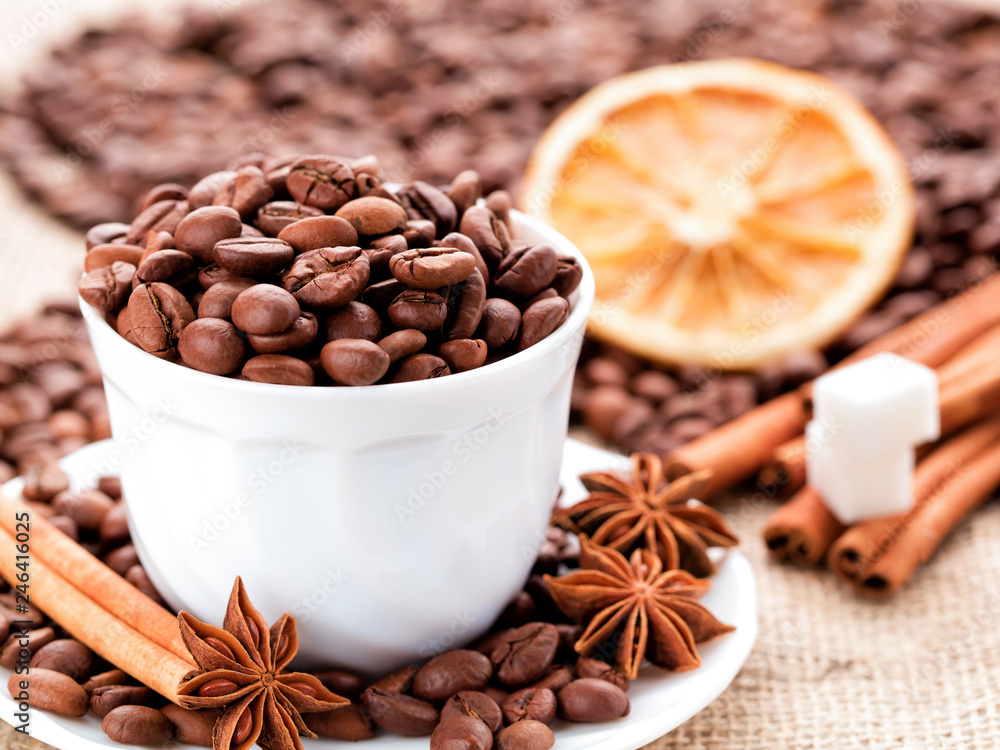 Fototapeta premium Grains coffee in cup. Cinnamon and anise on a dish. Dried lemon slices and sugar.