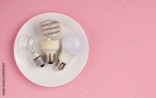 Incandescent lamp, fluorescent lamp and LED lamp in metaphor on technological progress on pink background with copy space