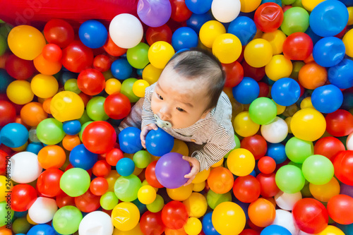 Asian baby playing in colorful ball pool