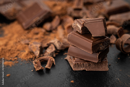 Broken chocolate pieces and cocoa powder on a dark background