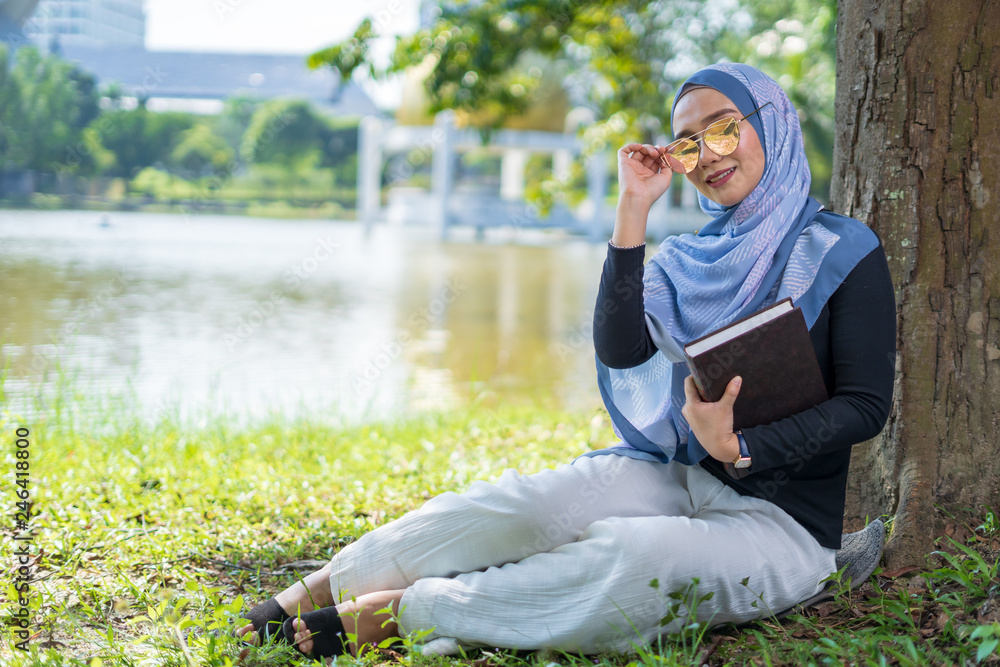 Attractive young woman reading book under the tree. Education concept.