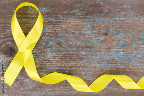 yellow ribbon-childhood cancer awareness symbol on the wooden background with copy space photo