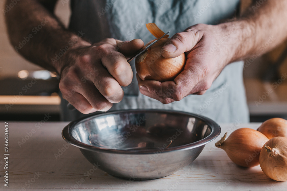 Onion in male hands close-up - cleaning and cutting process - rustic Onion in male hands close-up - cleaning and cutting process - rustic