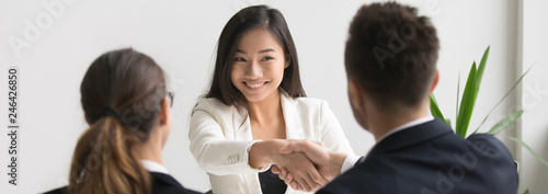 Smiling successful young asian applicant handshake with hr manager feels happy getting hired, boss congratulating employee new job employment concept. Horizontal photo banner for website header design