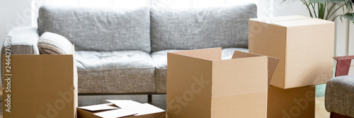 Horizontal photo heap of cardboard boxes with personal belongings in living room at moving relocation day no people, delivery service concept, banner for website header design with copy space for text