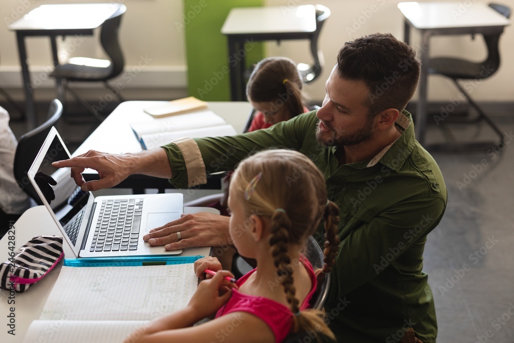 Young school teacher helping girl with study on laptop in Young school teacher helping girl with study on laptop in