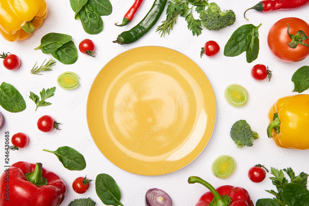 Flat lay with yellow plate and vegetables on white background