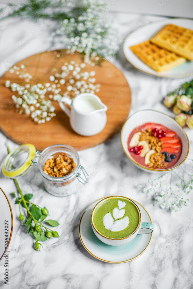 spring breakfast on the table with green tea latte with oatmeal, waffles and flowers