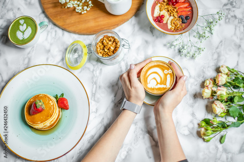 Wallpaper Mural a cup of coffee with milk in hand, pancakes and cereal with fruit on the table Torontodigital.ca