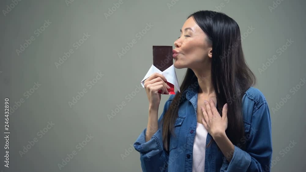 Funny girl enjoying sweet aroma of chocolate bar, kissing it, woman keeping diet Funny girl enjoying sweet aroma of chocolate bar, kissing it, woman keeping diet