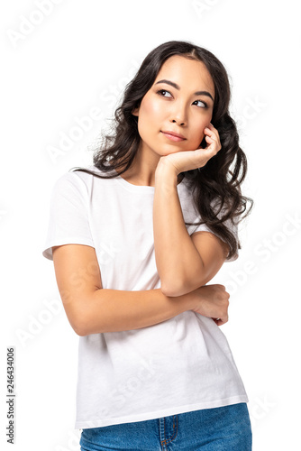 Pensive young asian woman in white t-shirt holding hand under chin isolated on white © LIGHTFIELD STUDIOS
