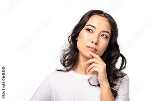 thoughtful young asian woman touching chin by hand isolated on white