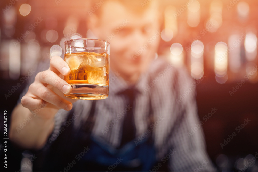 Barman serves client, gives glass of whiskey with ice double portion